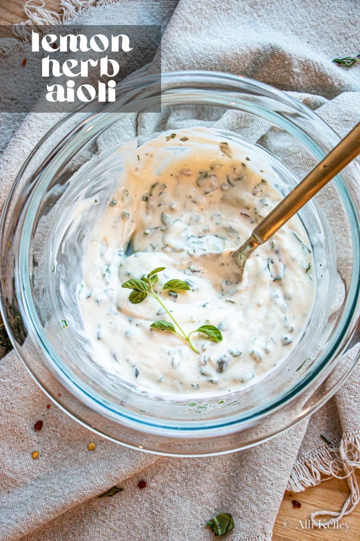 a glass bowl filled with white sauce on top of a wooden table next to a towel