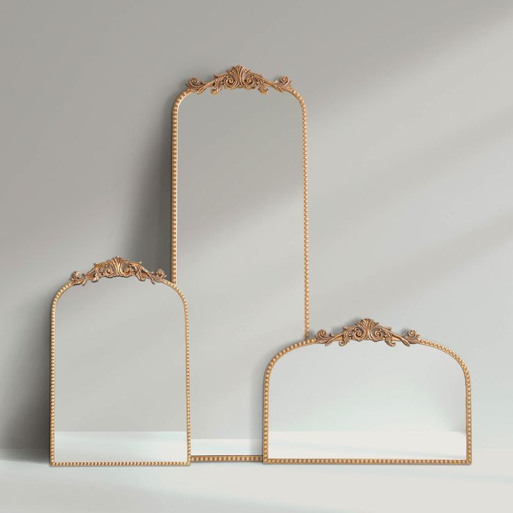 two mirrors sitting next to each other on top of a white table with gold trimmings