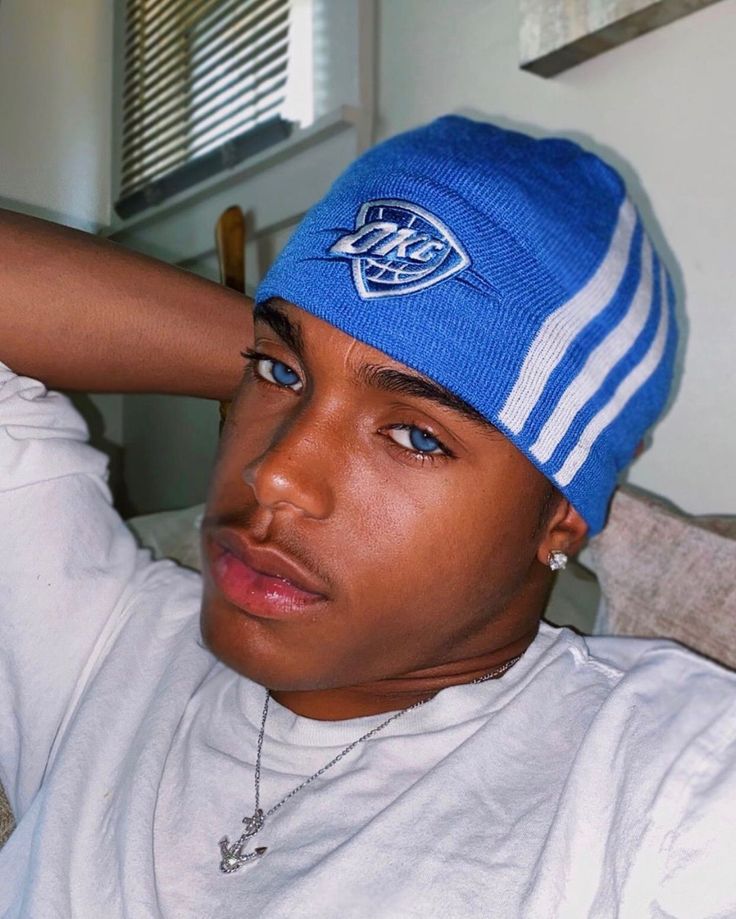 a young man wearing a blue and white striped beanie with his hand on his head