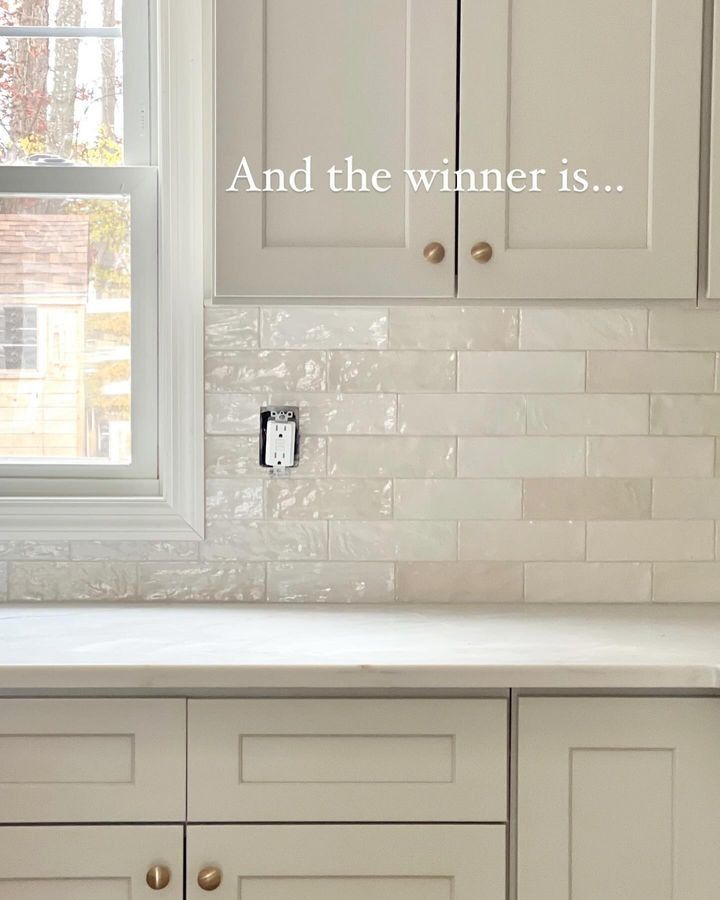 a kitchen with white cabinets and tile backsplashing that says and the winner is