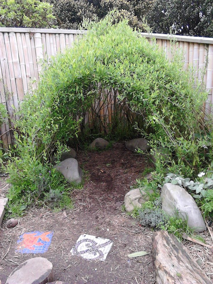 a small garden with rocks and plants in the middle, near a fenced area