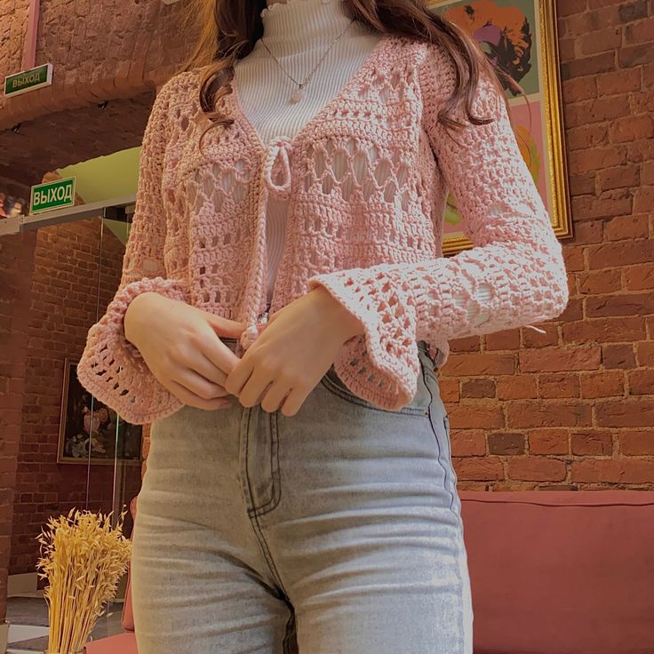 a woman in jeans and a pink sweater is posing for the camera with her hands on her hips