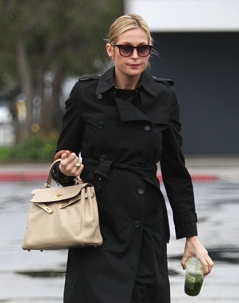 a woman is walking down the street with a handbag and bottle in her hand