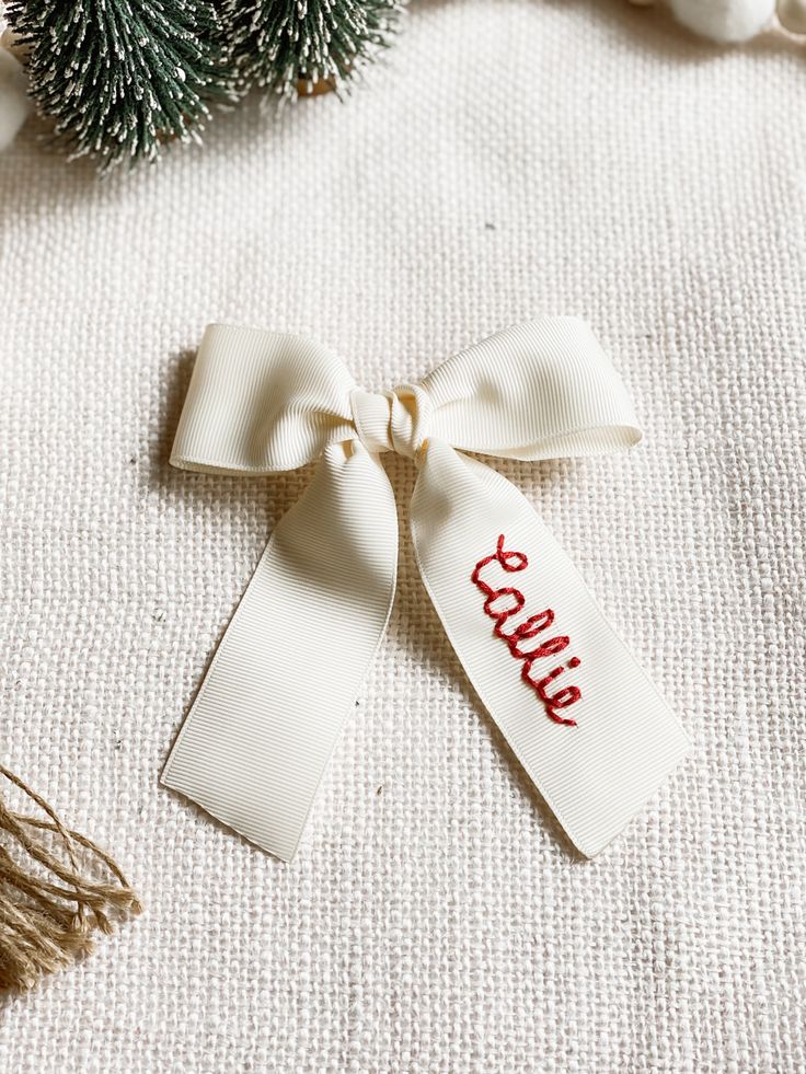 a white ribbon with the word hello written on it next to some pine cones and other christmas decorations