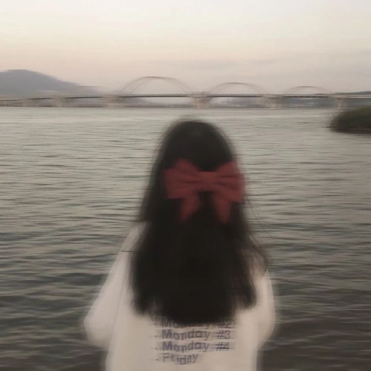 a woman with a red bow standing in front of the water