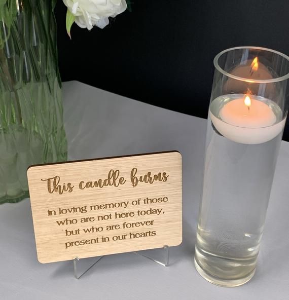 there is a candle that is next to a vase with flowers in it and a sign on the table