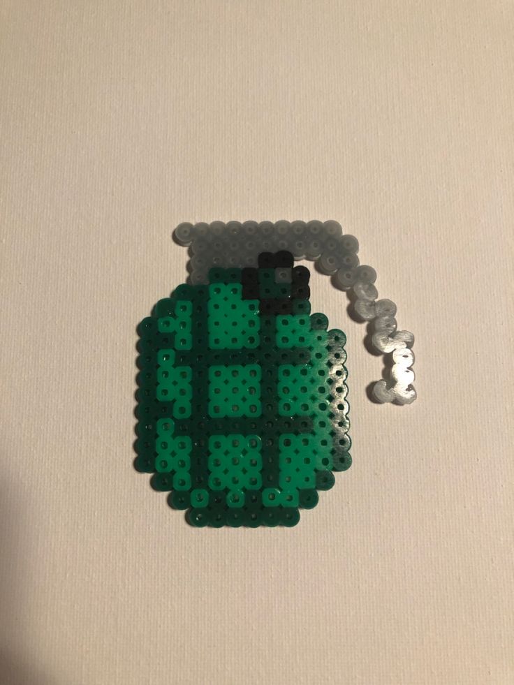 a green object made out of legos sitting on top of a white tablecloth