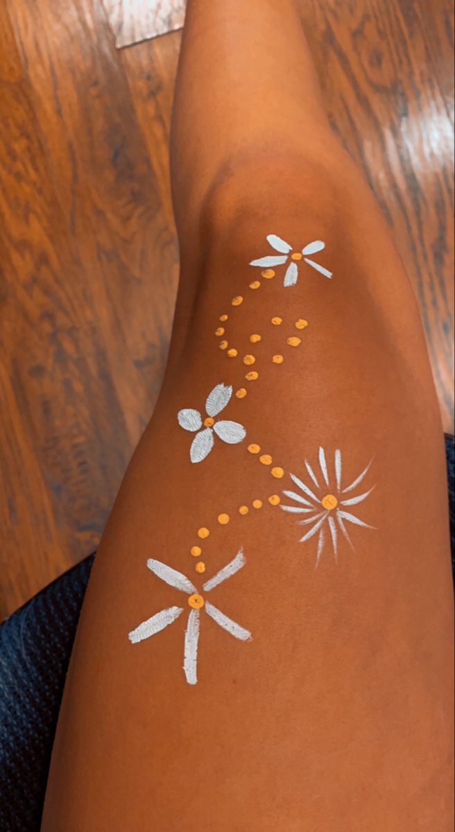 a woman's legs with white paint on them and flowers painted on the skin