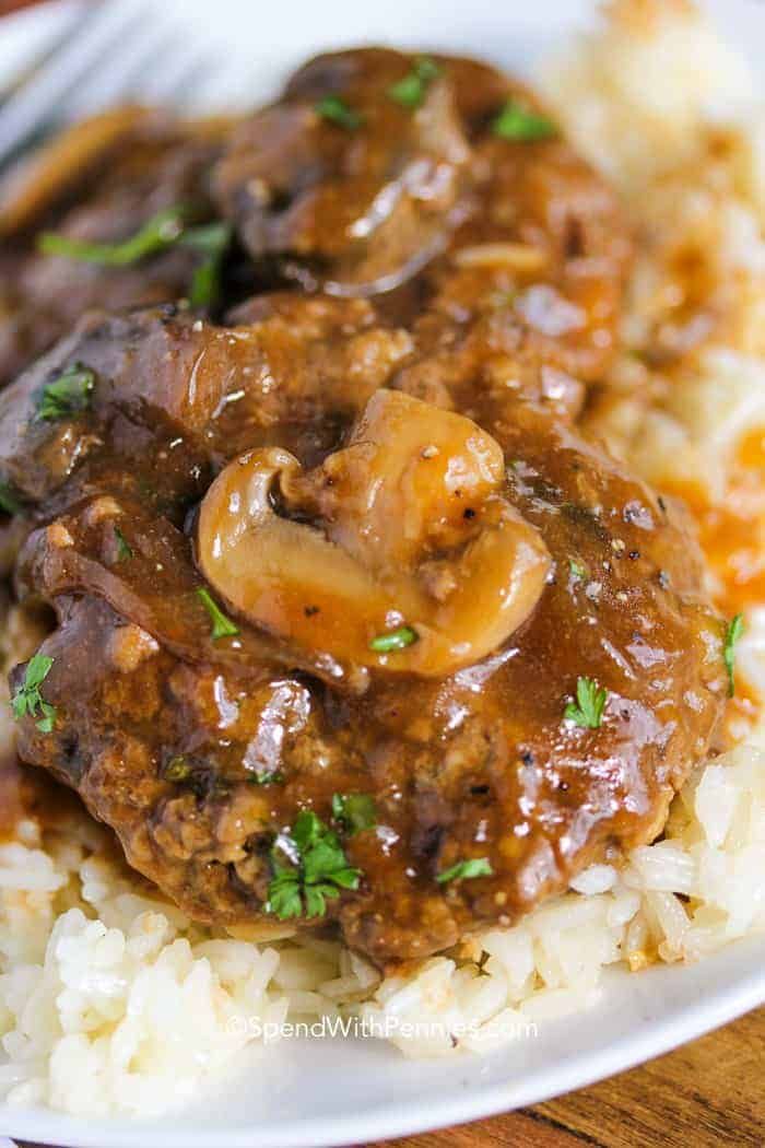 a plate with meat and mushrooms on top of mashed potatoes, garnished with parsley