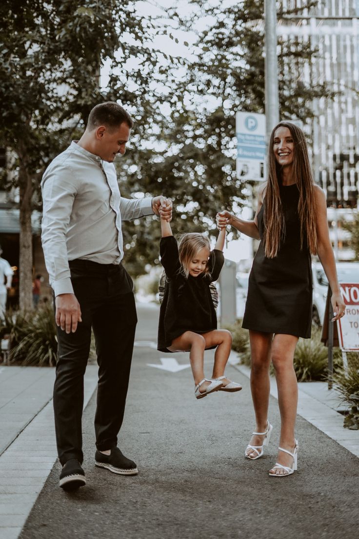 a man, woman and child are standing on the sidewalk