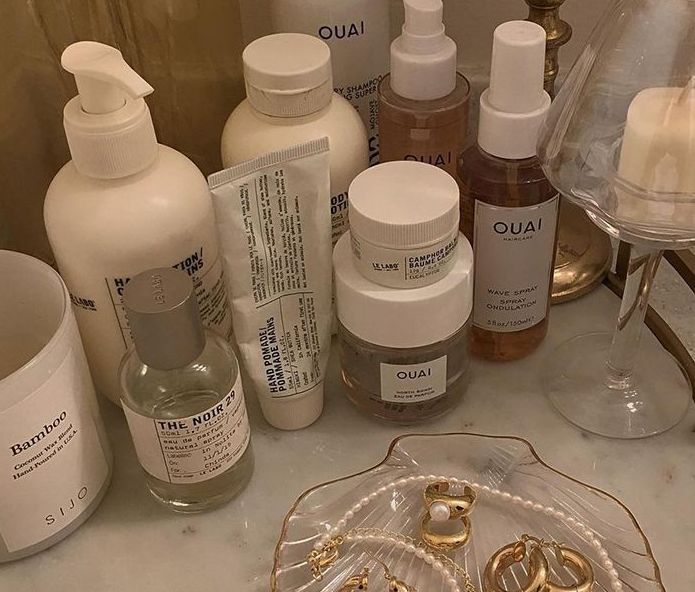 various skin care products are sitting on a counter top next to a glass plate with gold rings