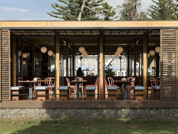 an outdoor dining area with chairs and tables on the outside, in front of some trees