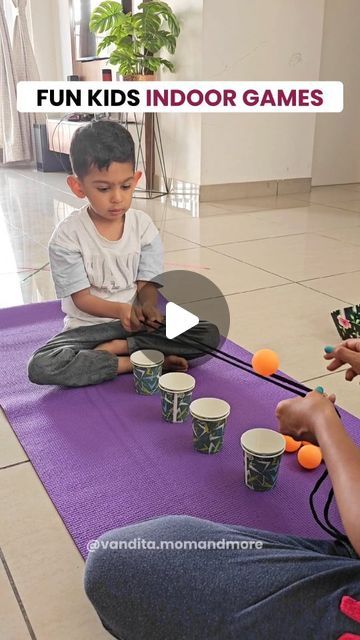 two children sitting on a purple mat playing with orange balls in front of an adult