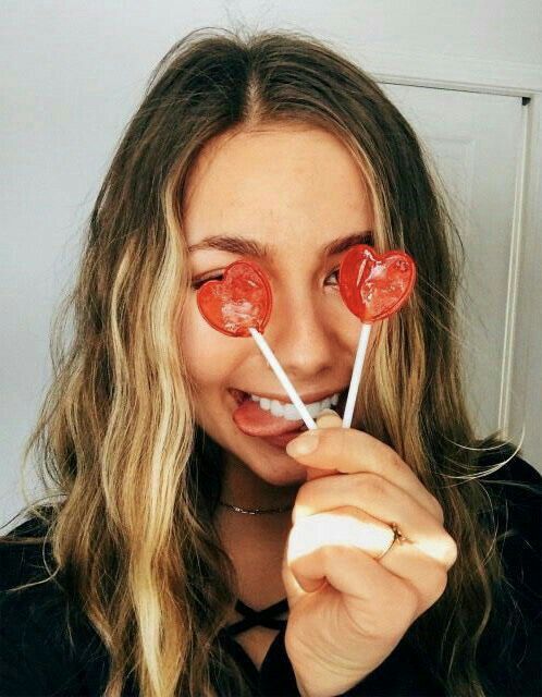 a woman holding two lollipops in front of her face