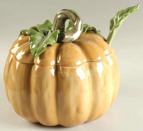 a ceramic pumpkin container with green leaves on top