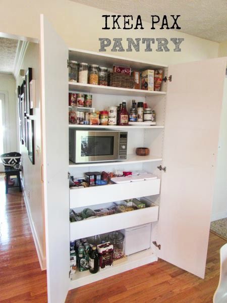 an open pantry with lots of food on the shelves and in front of a microwave