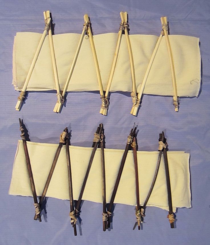 six pairs of knitting needles are laid out on a blue tablecloth with white fabric