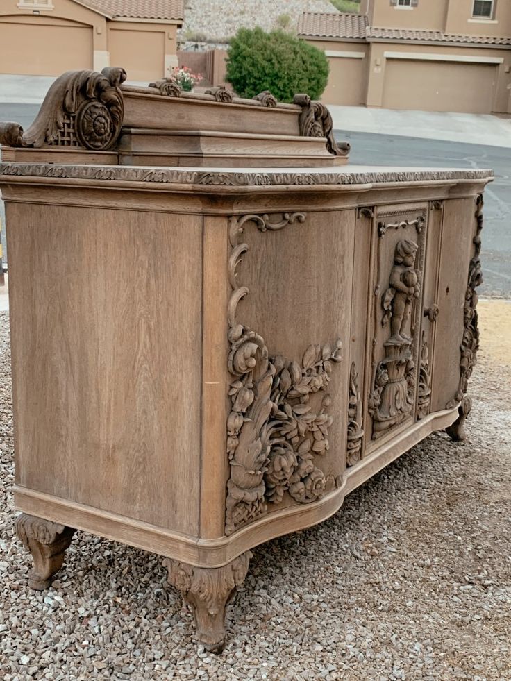 an old wooden chest with carvings on the front and sides sitting in gravel next to a building