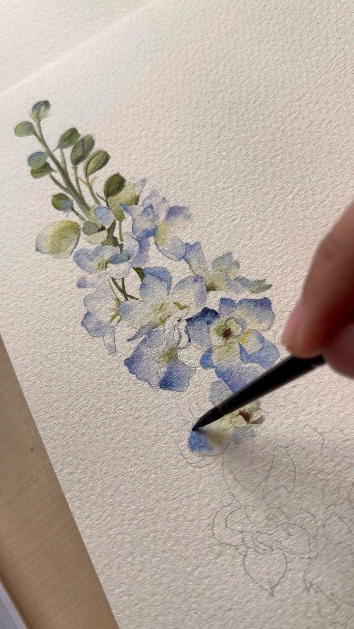 someone is drawing flowers with watercolors on paper