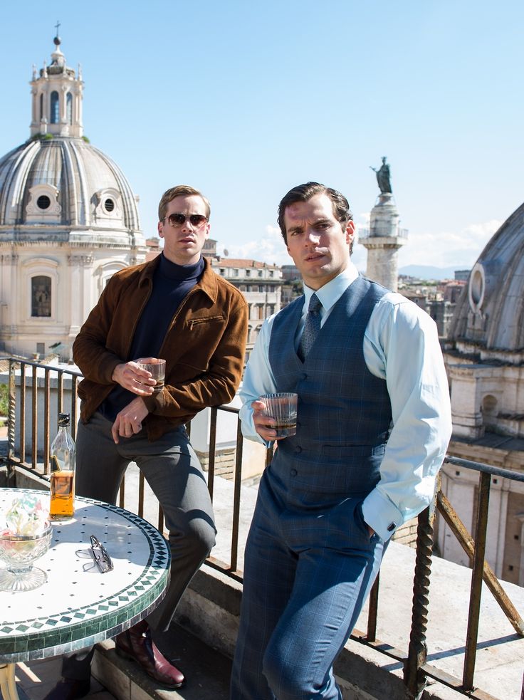 three men are sitting at a table on a balcony overlooking the dome of a building