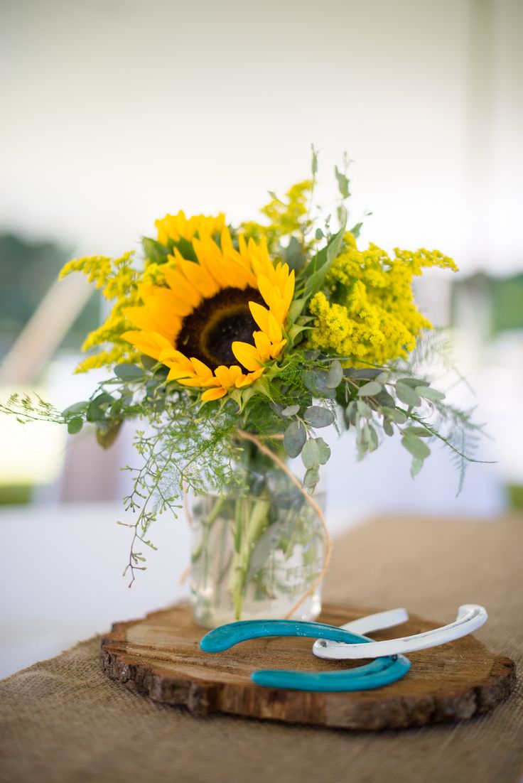 a vase filled with yellow flowers sitting on top of a wooden cutting board next to scissors