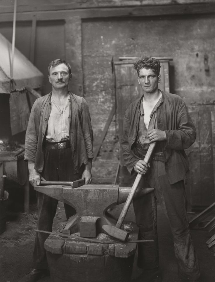 two men standing next to each other holding tools