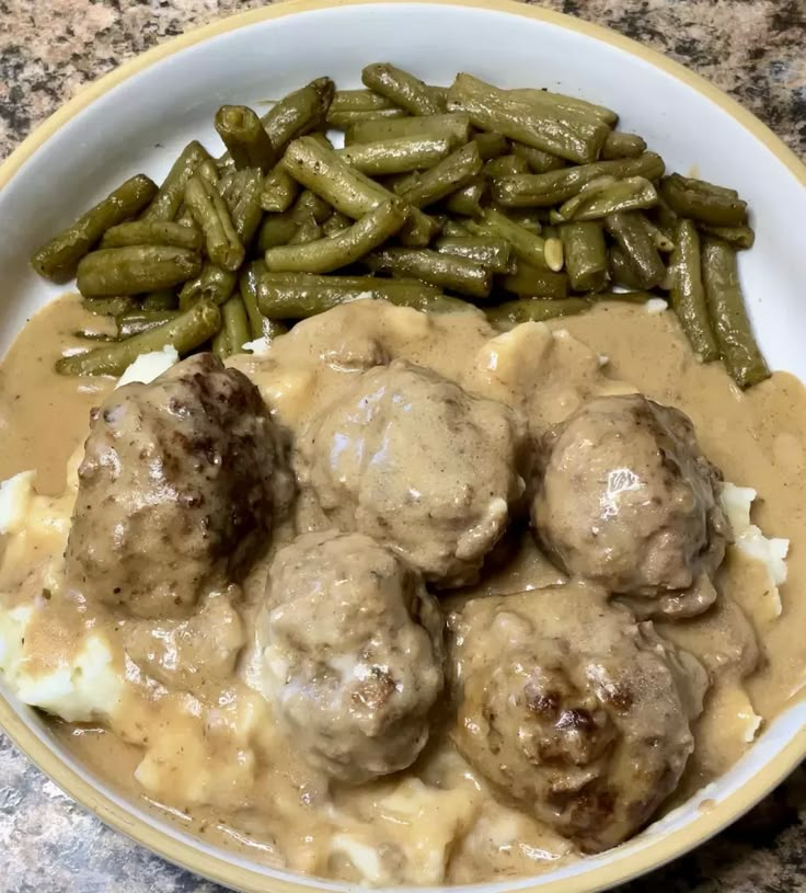 meatballs, mashed potatoes and green beans are in a bowl on the table