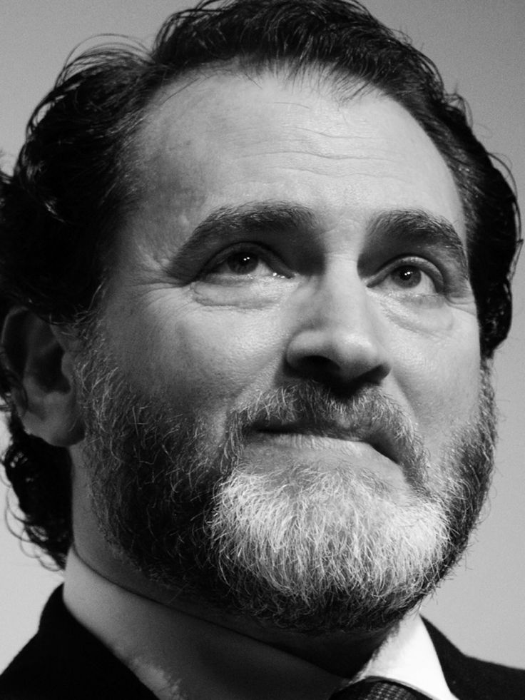 a black and white photo of a man with a beard wearing a suit and tie