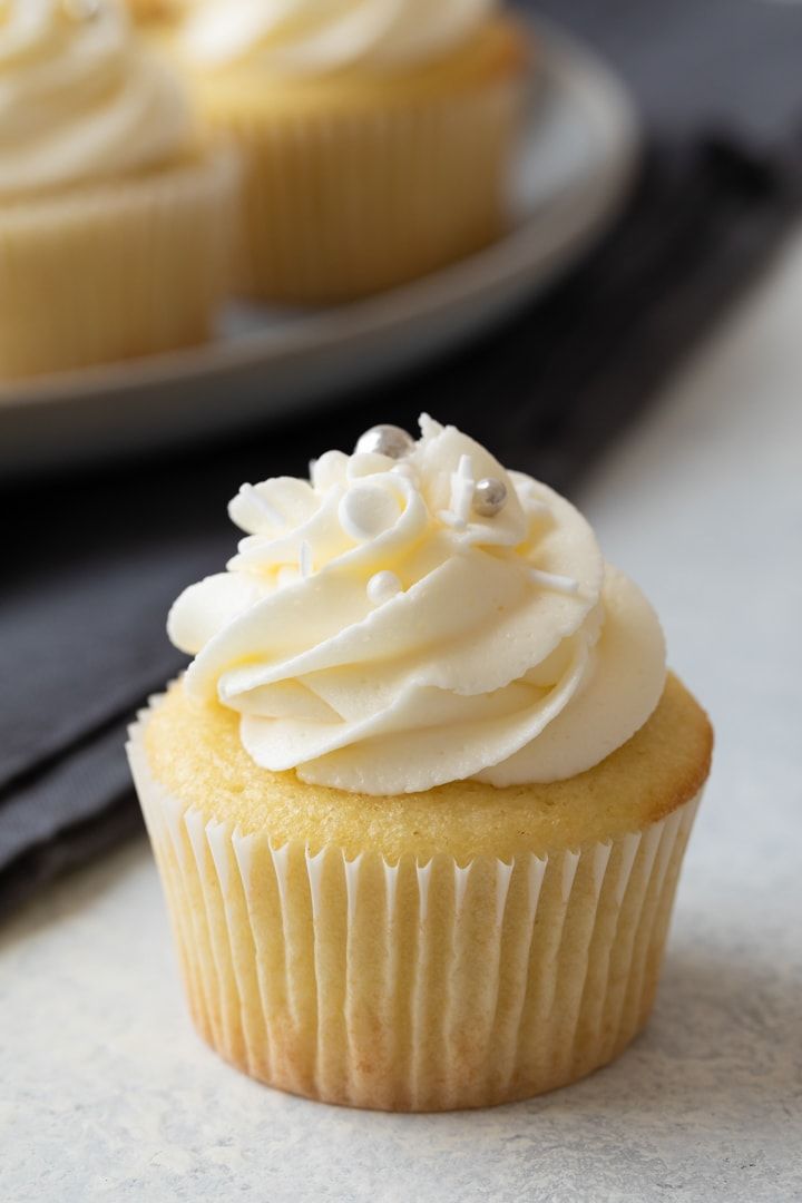 two cupcakes with white frosting sitting on a plate next to each other