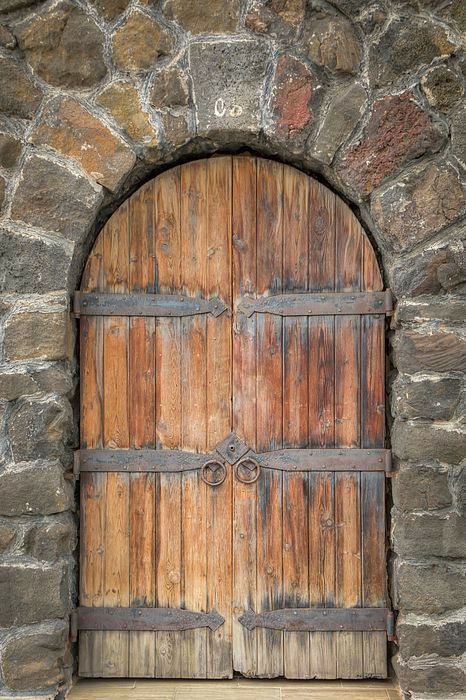 an arched wooden door in a stone wall