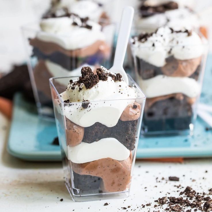 three desserts in plastic cups on a blue tray