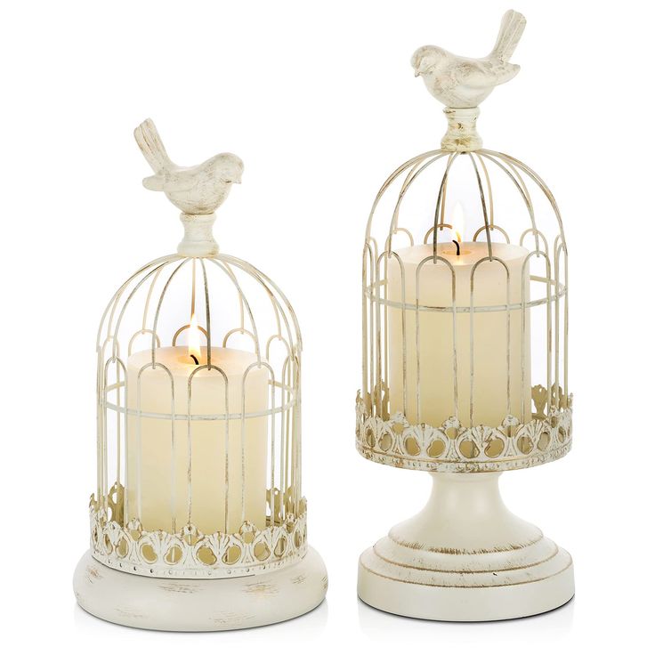 two white candles are in a birdcage