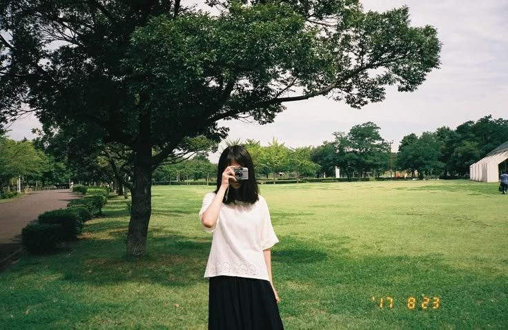 a woman standing in the grass taking a photo