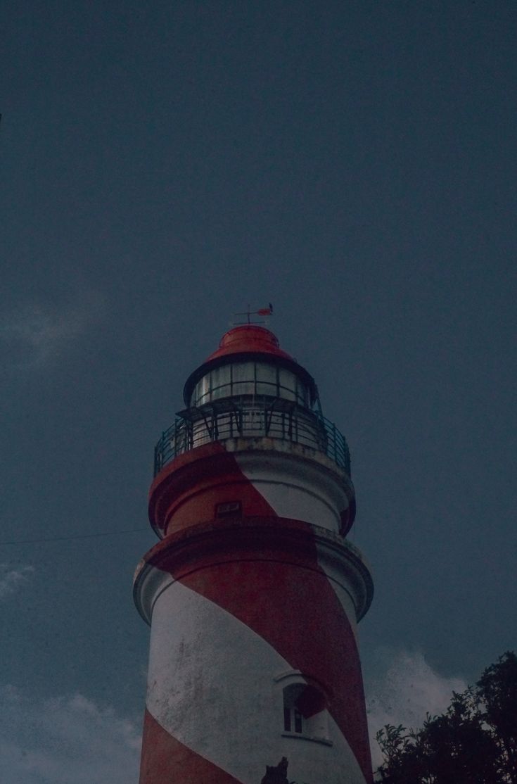 a red and white lighthouse under a cloudy blue sky