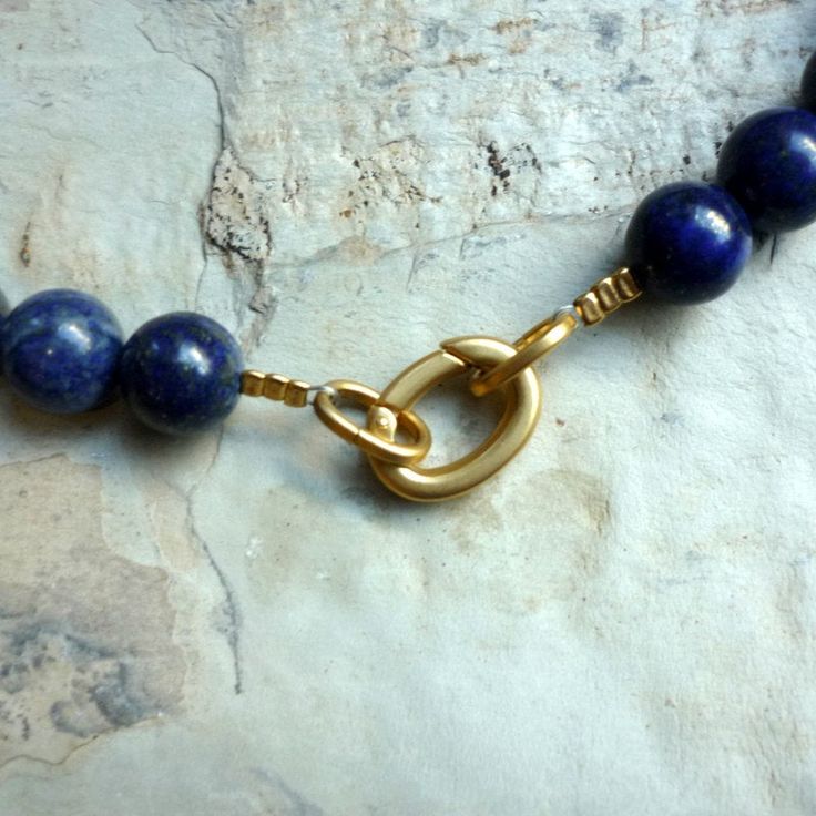 "This is a stunning Lapis Lazuli beaded necklace. The deep blue colour is accompanied by gold plated floral spacer beads. The spacers add an added touch of gold colour to complement the Lapis. Small flecks of gold are found throughout the stone beads and add to it's unique one of a kind nature. The clasp in the back is also gold plated and very easy to use. A great statement piece for both daytime and evening. Dimensions: Length - 17.75 \" Approximate diameter of stones: 1.2 cm extender- an exte Gold Single Strand Lapis Lazuli Beaded Necklace, Elegant Gold Beaded Necklaces With Lapis Lazuli, Lapis Lazuli Single Strand Beads For Gifts, Single Strand Lapis Lazuli Beads For Gift, Blue Lapis Lazuli Necklace With Spacer Beads, Blue Lapis Lazuli Single Strand Beads, Blue Single Strand Lapis Lazuli Beads, Single Strand Blue Lapis Lazuli Beads, Lapis Lazuli Necklace With Spacer Beads