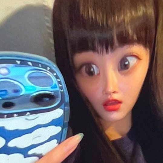 a close up of a doll holding a cell phone in her hand and looking at the camera