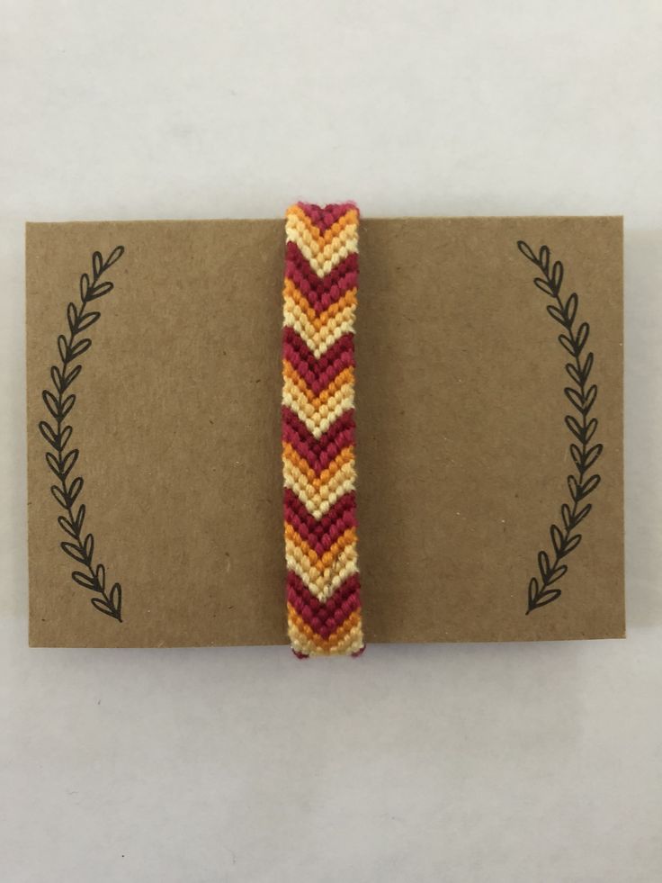 a piece of crafting paper with a beaded bracelet on it's side