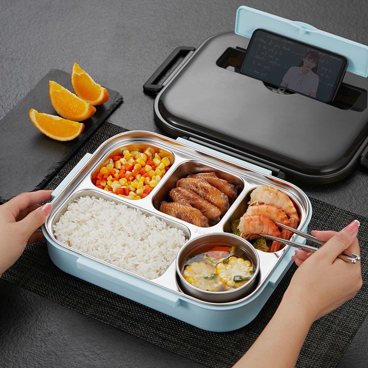 a person is holding a fork over a bento box filled with food