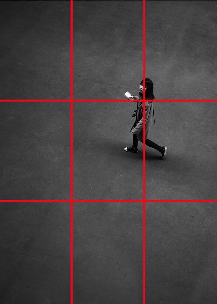 a woman walking across a tarmac with red lines on the floor and in front of her