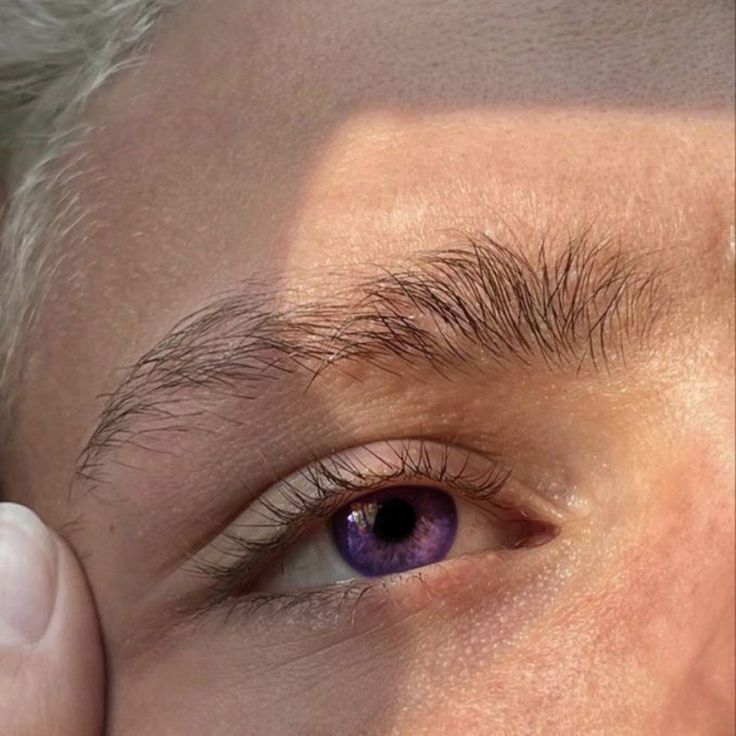 an older man with gray hair and brown eyes is holding his hand to his eye