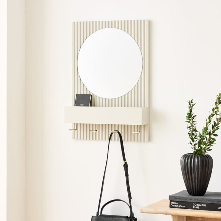 a black handbag sitting on top of a table next to a mirror and plant