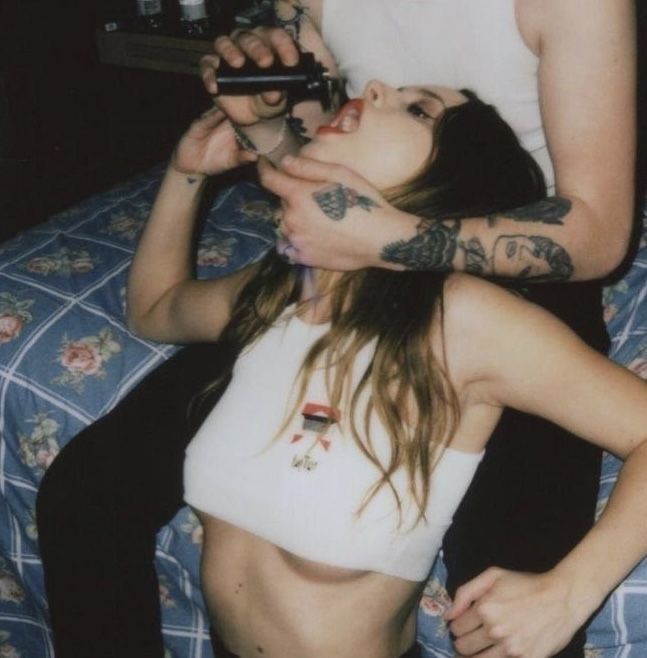 a man and woman sitting on top of a bed next to each other with tattoos on their arms