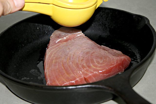 a piece of meat is being cooked in a skillet with a yellow spatula