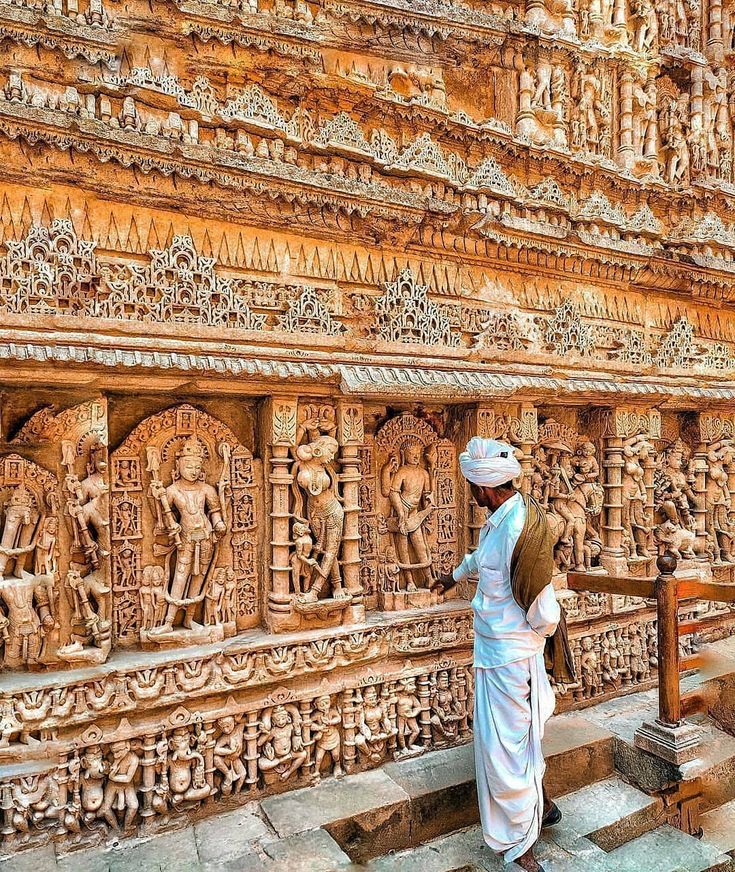 a man standing in front of an intricately carved wall with carvings on it's sides