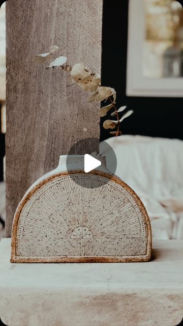 an old fan sitting on top of a table next to a vase with flowers in it