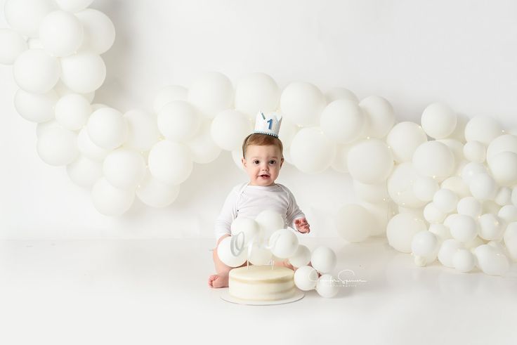 a baby sitting in front of white balloons