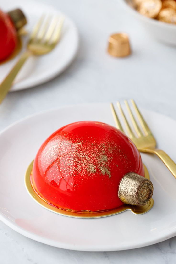 a white plate topped with a red dessert covered in gold flecks next to a fork