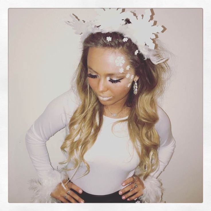 a woman with long blonde hair wearing a white top and feathered headpieces