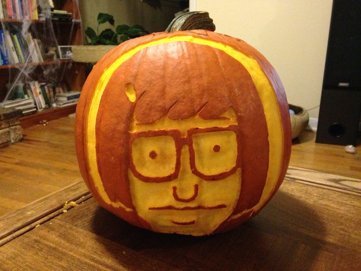 a pumpkin carved to look like a man with glasses on it's face, sitting on a table