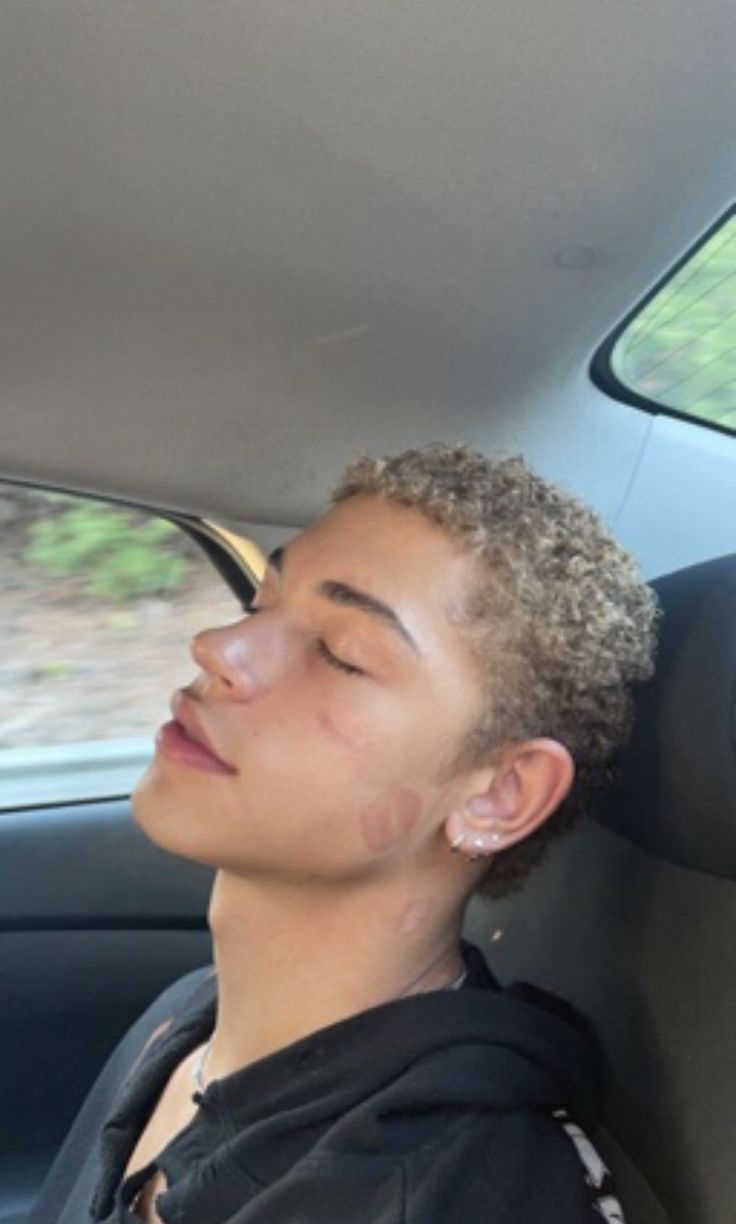 a young man sitting in the back seat of a car with his eyes closed and head turned to the side